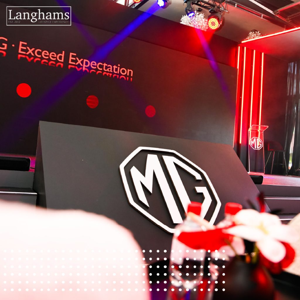 Stylish automotive brand launch event at Langhams featuring the MG stage setup with dramatic red lighting and branded podium